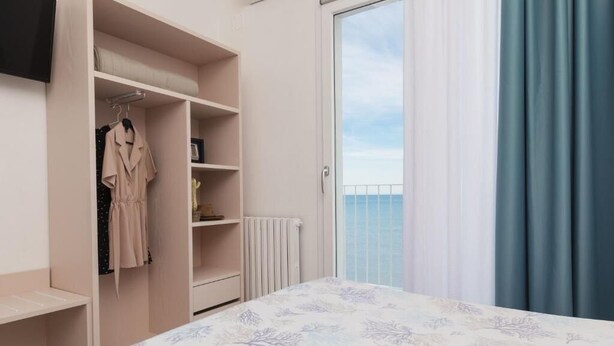Un dormitorio con cama, armario y vistas al mar a través de un ventanal corredera.