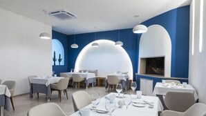 Un comedor moderno con mesas dispuestas para el servicio, que presenta una decoración en tonos azul y blanco e iluminación contemporánea.