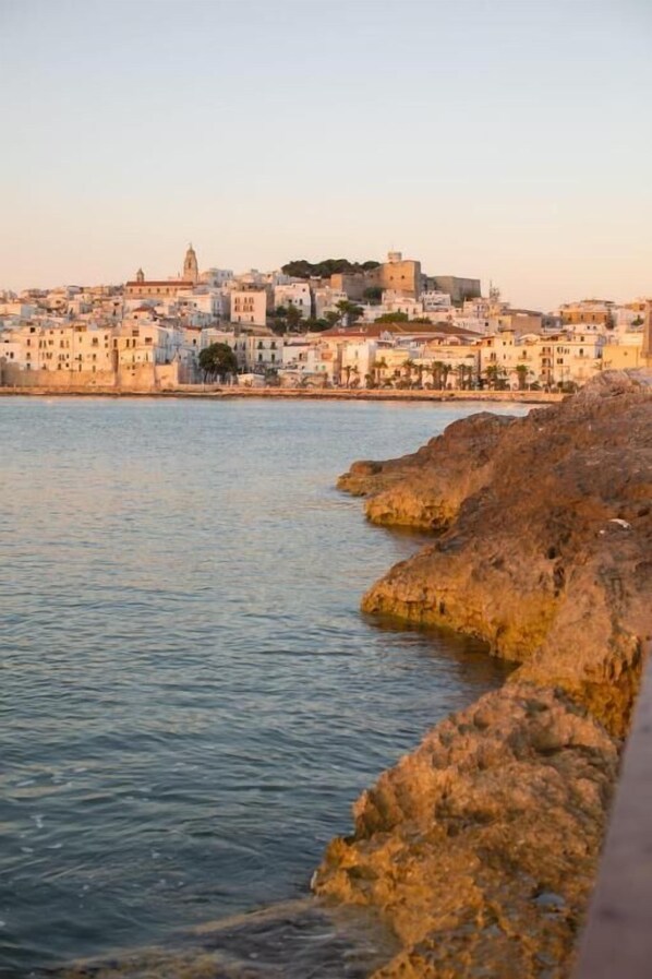 A coastal town with buildings along the water, rocky shores, and a prominent building with a tower. - Hotiday Vieste Lungomare  (Vieste)