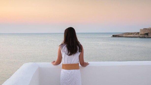 A person standing on a balcony overlooking a calm sea with a sunset in the background. - Hotiday Vieste Lungomare  (Vieste)