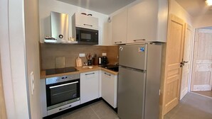 Cocina compacta con horno integrado, microondas y refrigerador de acero inoxidable.