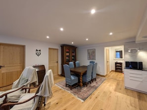 A dining area with a wooden table and chairs, a cabinet, and a television in a separate room.