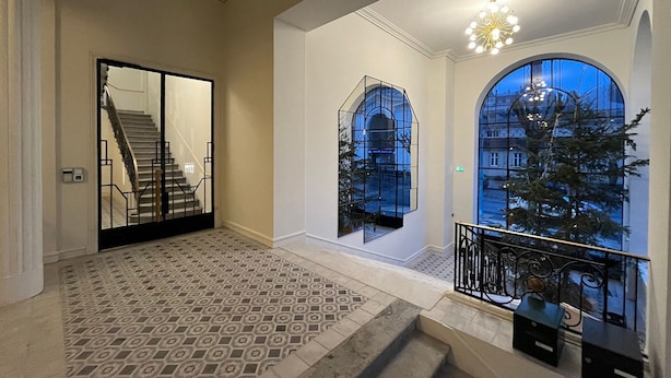 Ein geräumiges Interieur mit einem gemusterten Boden, einer Treppe und einem Balkon mit Geländer.