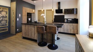 Eine moderne Küche mit Holzschränken, einer zentralen Kochinsel mit Barhocker, einem Einbauofen und einer Mikrowelle.