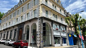 Ein historisches Gebäude mit einer symmetrischen Fassade, mehreren Balkonen und großen Fenstern.
