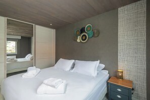 Ett hotellrum med en säng, ett nattduksbord, en spegel och en väggdekoration.