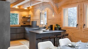 Cocina moderna con vigas de madera, una isla central y ventanas amplias.