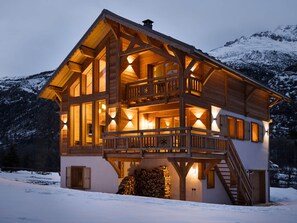 Eine Holzhütte mit Balkon, großen Fenstern und einer Treppe, die zu einer oberen Ebene führt.