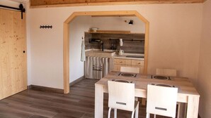 Eine kleine Küche mit Holzschränken, einem Esstisch mit Stühlen und einer Arbeitsplatte.