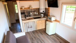 Eine kleine Küchenzeile mit Spüle, Kaffeemaschine, Toaster und kleinem Kühlschrank.
