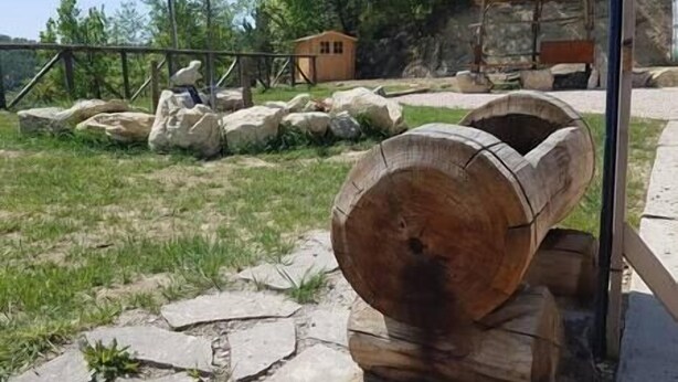 A large wooden log structure in a natural setting with rocks and a small wooden shelter in the background. - Straw apartment (Mercato Saraceno)