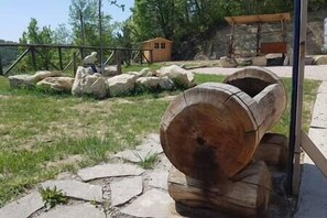 A large wooden log structure in a natural setting with rocks and a small wooden shelter in the background. - Straw Apartment (Mercato Saraceno)