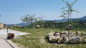 A paved pathway leading to a grassy area with a wooden fence and rocks. - Straw apartment (Mercato Saraceno)