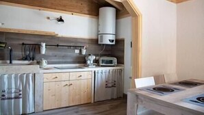A compact kitchen with wooden cabinets, a built-in stove, and a microwave. - Straw apartment (Mercato Saraceno)