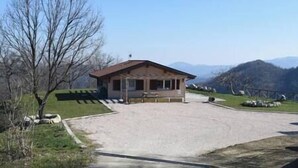 A small, single-story building with a sloped roof, situated in a rural setting with a gravel driveway leading to it. - Straw apartment (Mercato Saraceno)