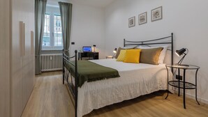 Een slaapkamer met een bed, nachtkastjes, een bureau en een radiator.