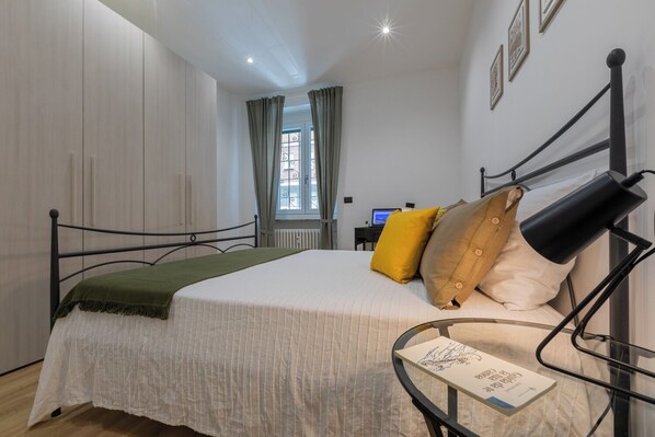 A bedroom with a bed, a desk with a computer, and a window with curtains. - Casa di Sisi by Wonderful Italy (Turin)