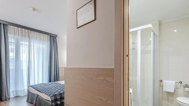 A hotel room with a bed, a shower, and a toilet. - Hotiday Torbole Lago (Nago-Torbole)