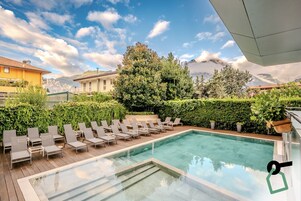 Una piscina al aire libre, sombrillas, sillones reclinables de piscina