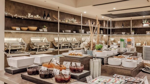 A buffet setup with various food items and serving utensils. - Hotiday Torbole Lago (Nago-Torbole)