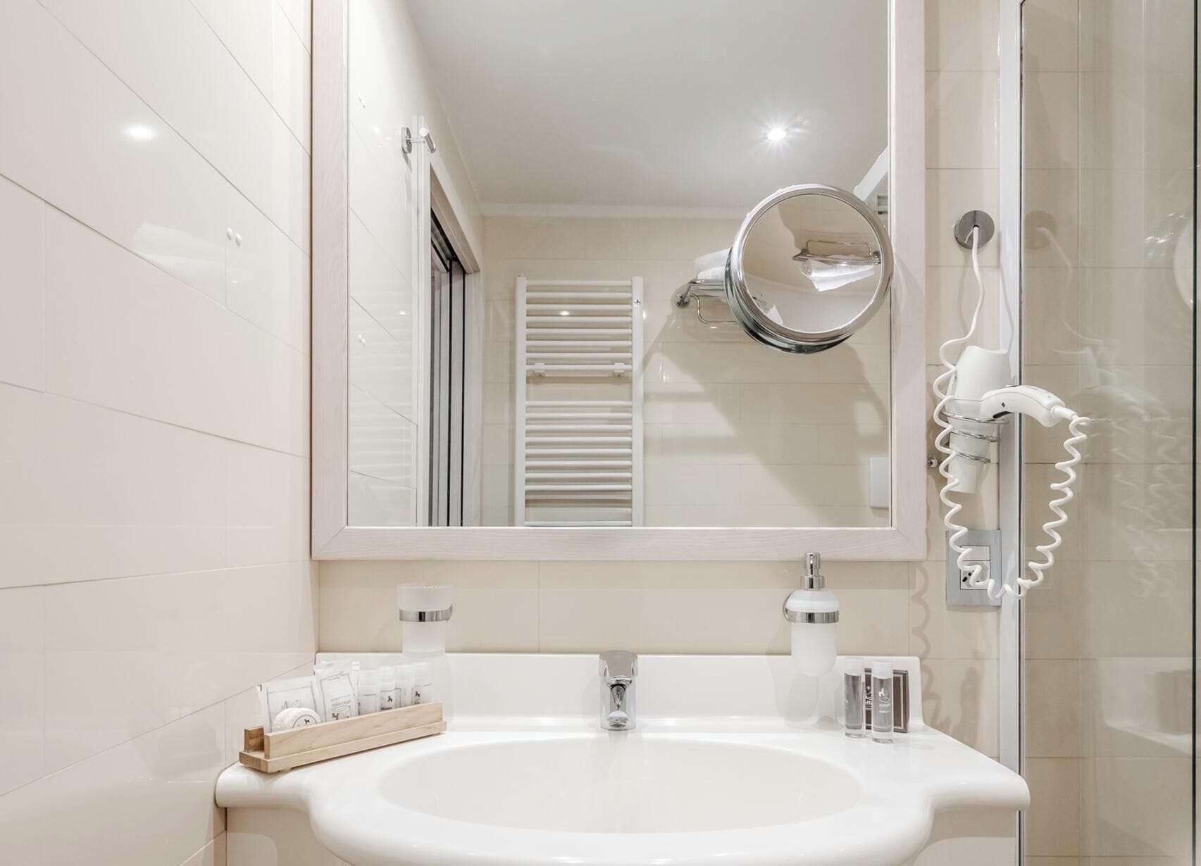 A bathroom with a white sink, a mirror, and a hairdryer.