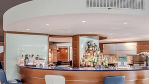 A bar area with a curved counter, bar stools, and a variety of bottles. - Hotiday Torbole Lago (Nago-Torbole)