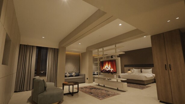 Ein modernes Wohnzimmer mit Flachbildfernseher, grauem Sofa, Couchtisch und Kamin.