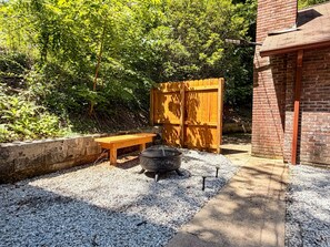 A patio area with a fire pit, a wooden bench, and a brick building. - Bryson Bungalow | Motorcycle Friendly | Downtown Bryson City | Polar Express (Bryson City)