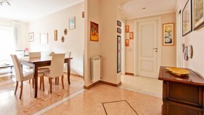A dining area with a wooden table and chairs, a radiator, and framed artwork on the walls. - Cozy apartment in the heart of the Marconi district.  (Roma)