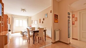 A spacious living area with a dining table and chairs, a fireplace, and a large window. - Cozy apartment in the heart of the Marconi district.  (Roma)