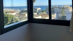 Une pièce dotée de grandes fenêtres donnant sur un port de plaisance et des immeubles.
