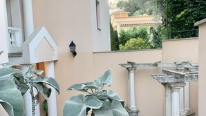 Une cour intérieure agrémentée de grandes plantes vertes, de colonnes blanches et d’un sol carrelé.