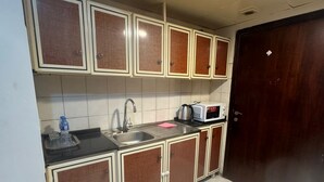 A compact kitchen with a sink, a microwave, and cabinets. - Furnished Studio Appartment in Burdubai  (Dubai)