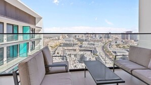 Een balkon met uitzicht op de stad, twee banken en een tafel.