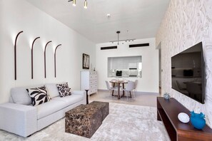 A modern living room with a sofa, coffee table, and a dining area with chairs and a table.