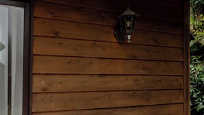 Un mur extérieur en bois, doté d’une fenêtre et d’un luminaire fixé au mur.
