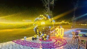 An outdoor area with a tiled floor, a decorative light structure, and a seating arrangement. - Royal stay farm house (Gurugram)
