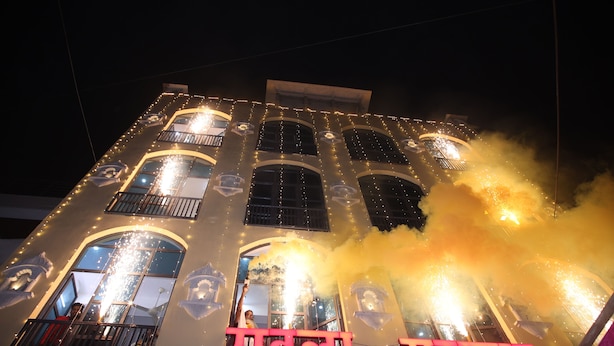A building with illuminated windows and balconies, featuring a prominent sign with text. - Rawla Sarkar (Udaipur)