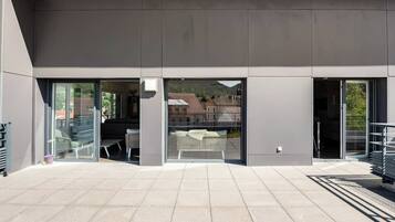 A modern building with large glass doors, a flat roof, and a paved outdoor area.