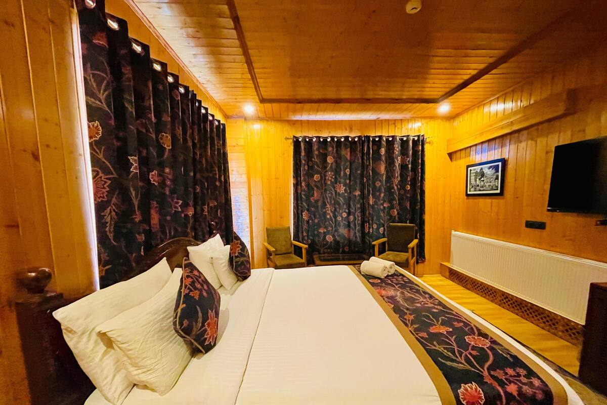 Una habitación con paneles de madera, una cama, una silla y un televisor en la pared.