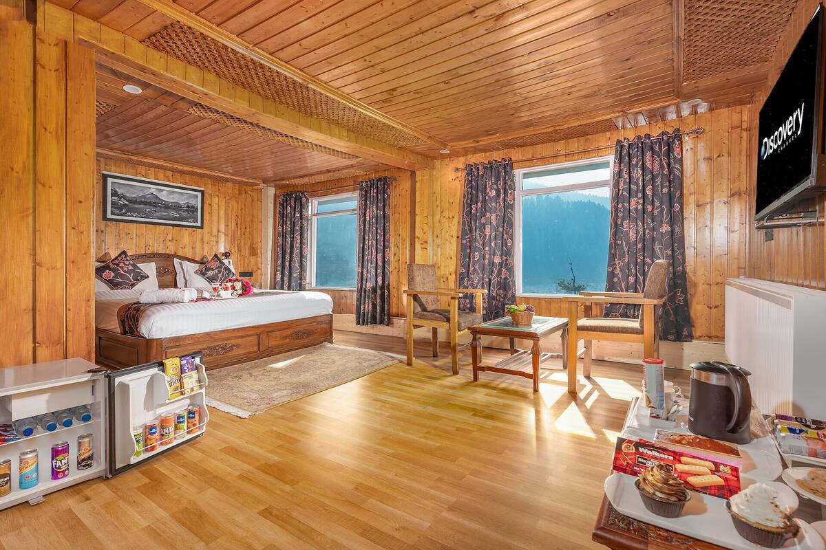 Una habitación de cabaña de madera con una cama, una mesa con alimentos para el desayuno y vistas a las montañas.