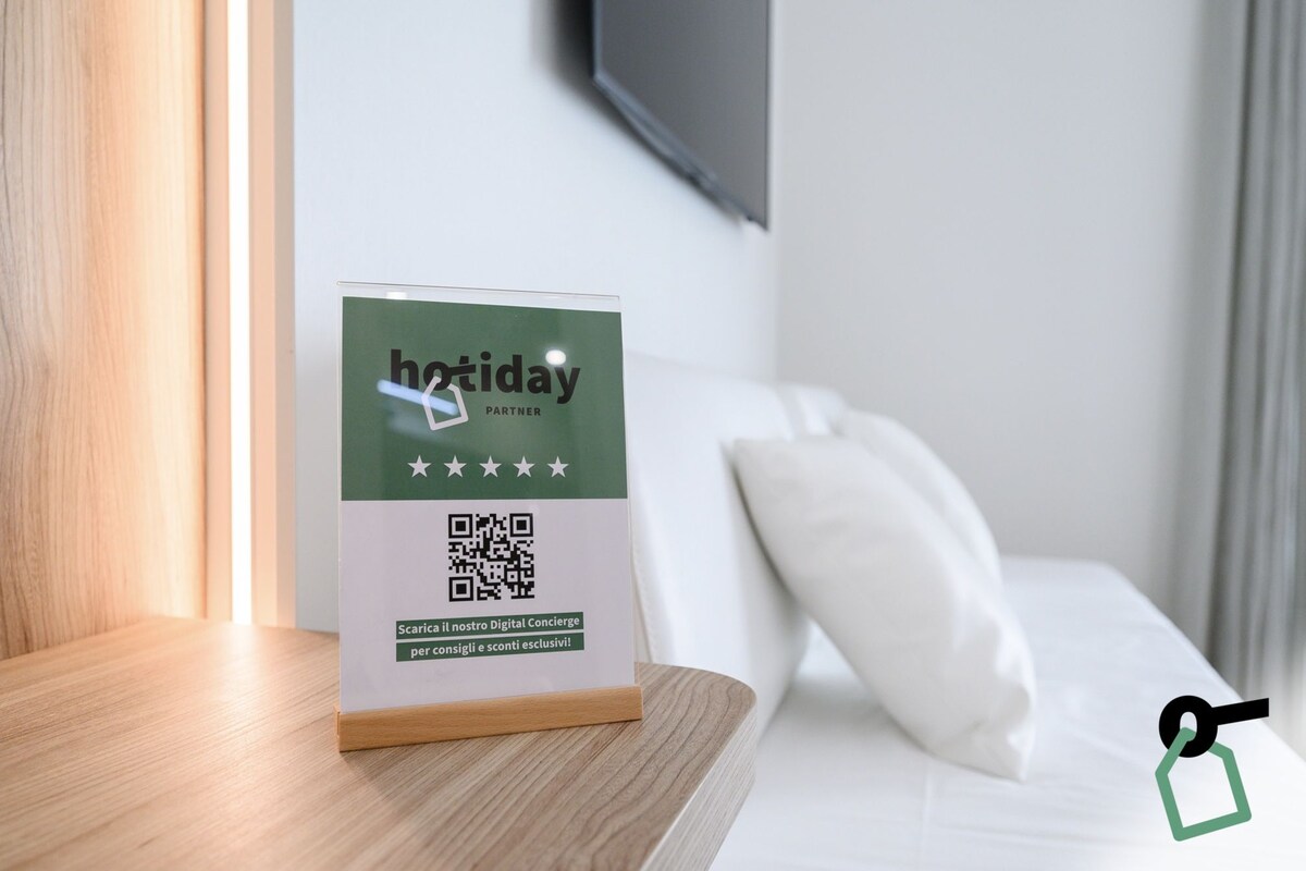 A hotel sign with a QR code and the text "hotday PARTNER" on a wooden table in a hotel room.