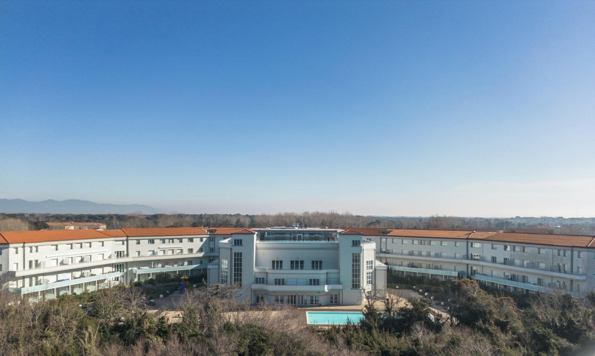 Un edificio grande con varios pisos, un patio central y una piscina.