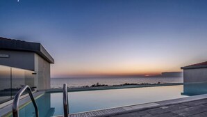 A pool area with a view of the ocean at sunset, wooden deck, and modern buildings. - Hotiday Room Collection - Tirrenia (Pisa)