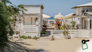 A beachfront property with wooden cabins, a sandy pathway, and a view of the sea. - Hotiday Room Collection - Tirrenia (Pisa)