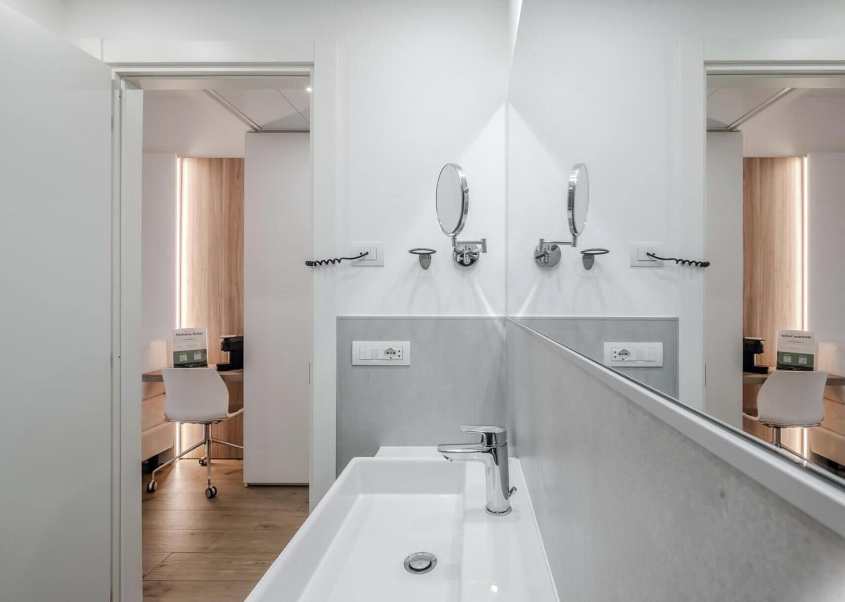 Un bagno moderno con uno specchio grande, un lavandino e una doccia.