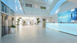 A spacious lobby with a high ceiling, a reception desk, and potted plants. - Hotiday Room Collection - Tirrenia (Pisa)