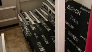 A bunk bed with striped bedding and a black sheet with city names.