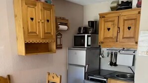 A compact kitchen with wooden cabinets, a refrigerator, a microwave, and a dishwasher.