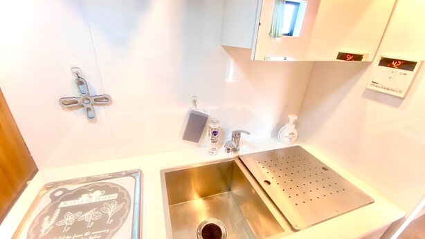 Una cocina con un lavamanos de acero inoxidable, una tetera y una cafetera.